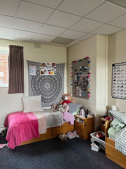 Cozy boarding school bedroom with bed, desk and personal decoration