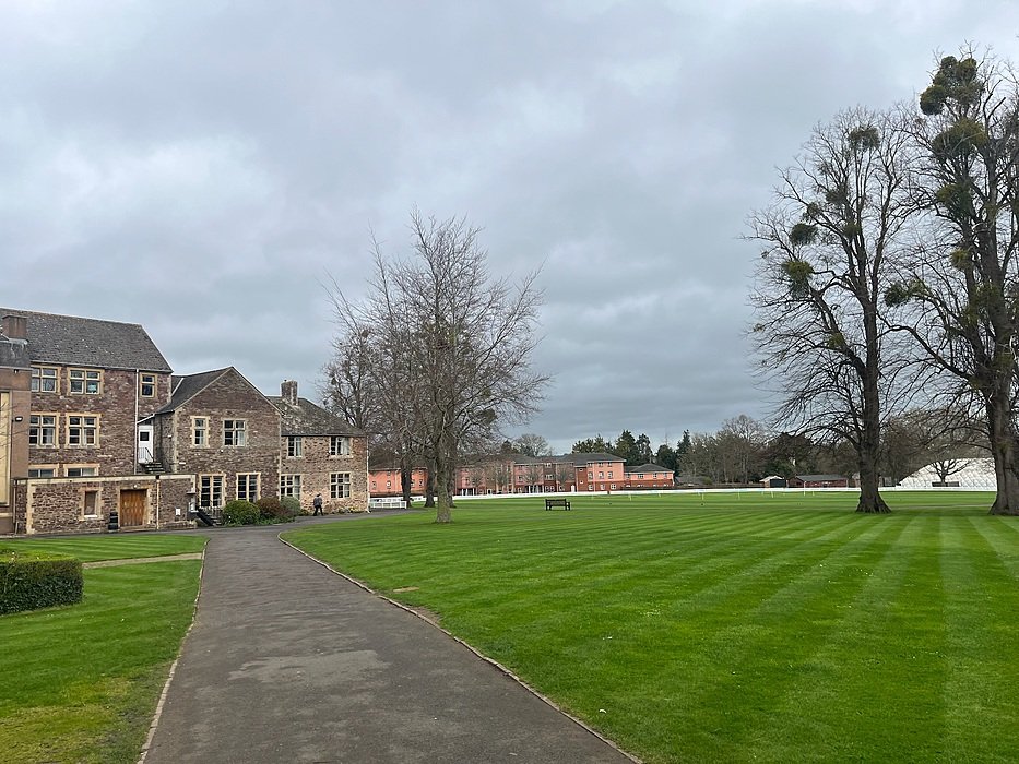Spacious school campus with lawns and historic buildings in the background