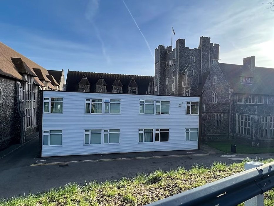a small modern white complex on a school campus surrounded by beautiful old buildings