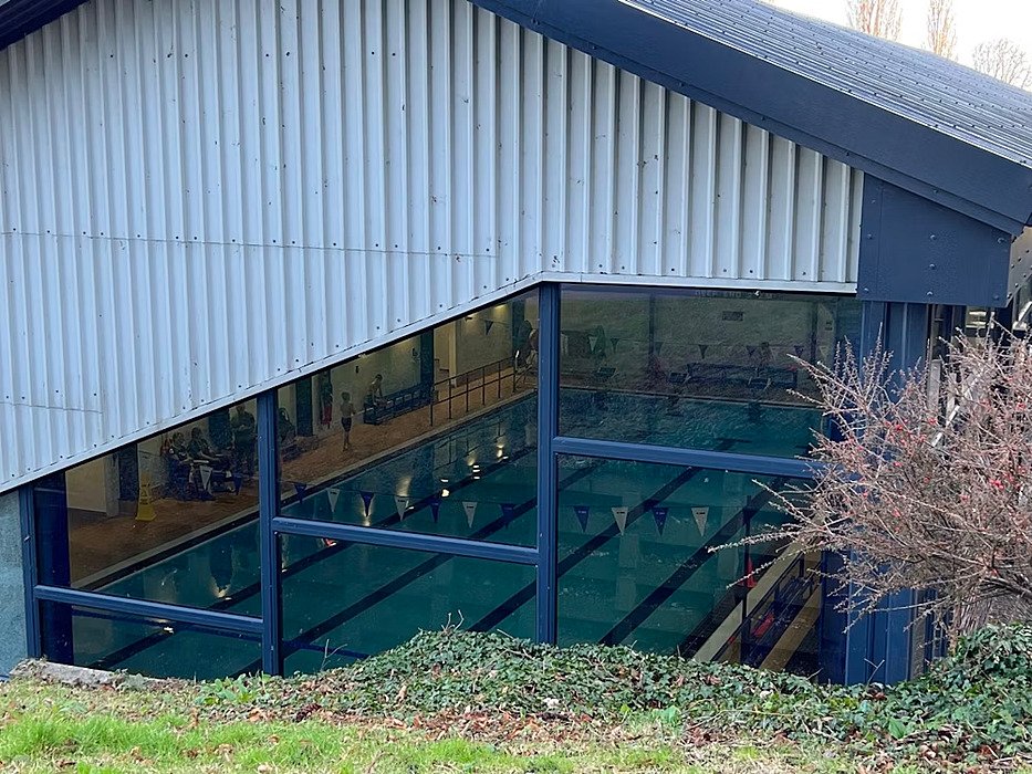 The big indoor swimming pool with huge windows seen from the outside