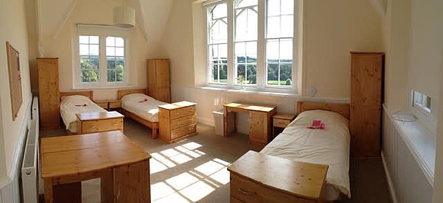 A bright boarding room with big windows and three beds ready for moving in