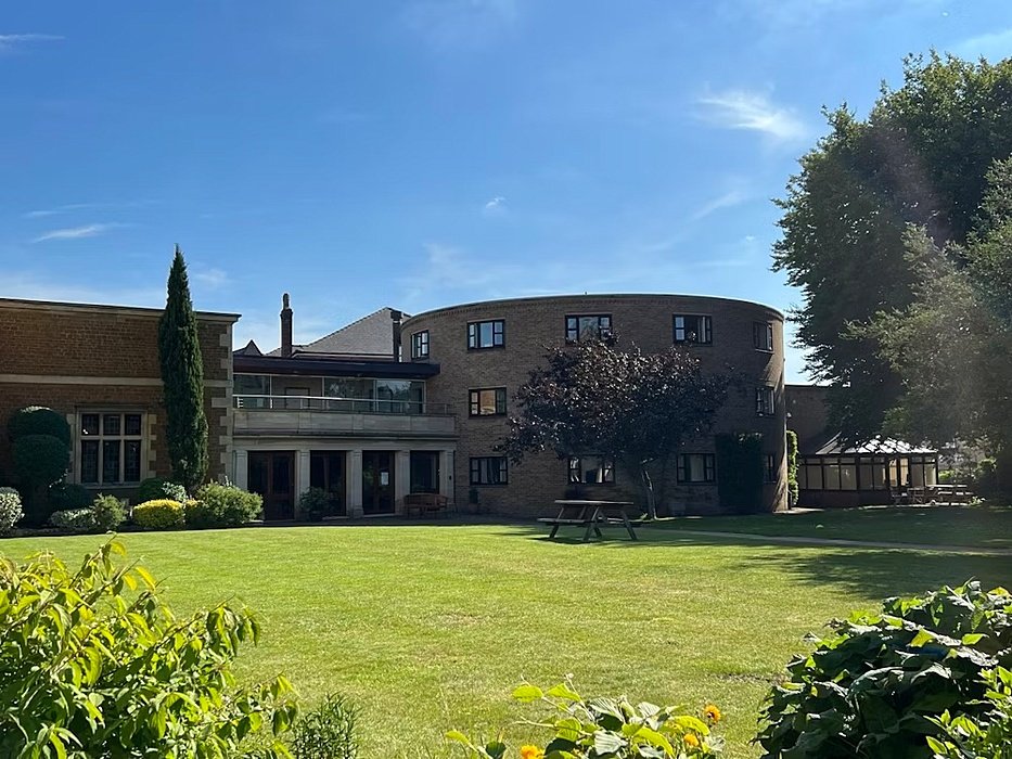 a green with a round shaped boarding house in the background