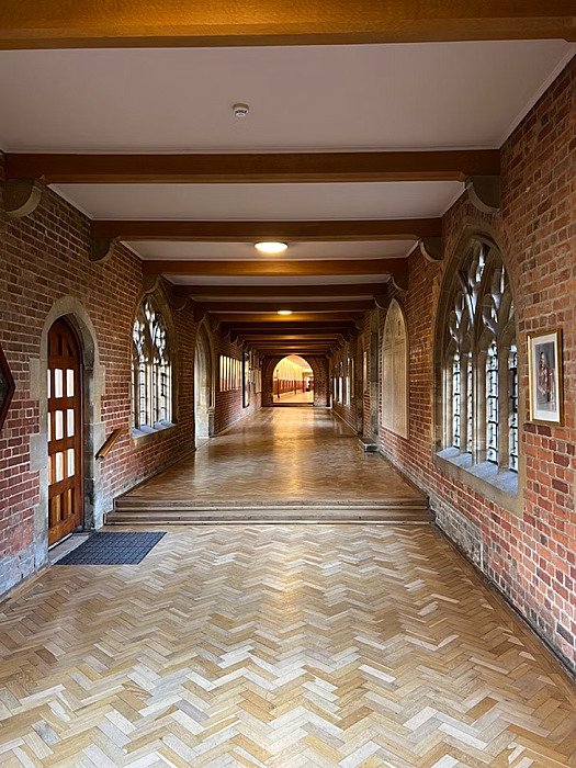 Hallway with gothic windows, brick walls, white ceiling with wooden beams and a parkett
