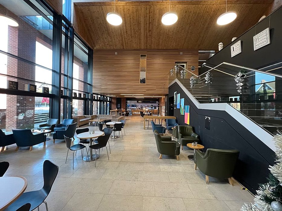 An open plan cafe, lots of wood, light black and metal impression