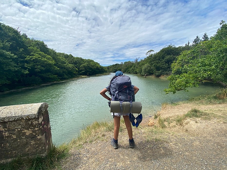 A Ryde School pupil with backpack looking at a lake