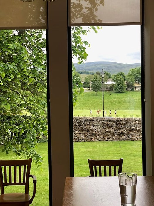 the view through a window with girls playing football on the pitch outside