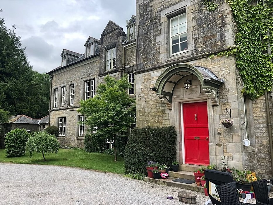 An old building with ivy on the walls and a red door