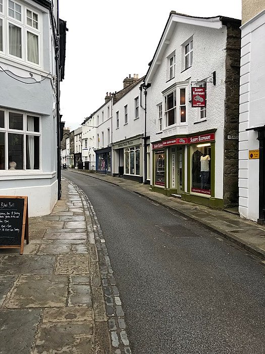 a pretty and narrow street with white houses and shop facades in the town of Sedbergh
