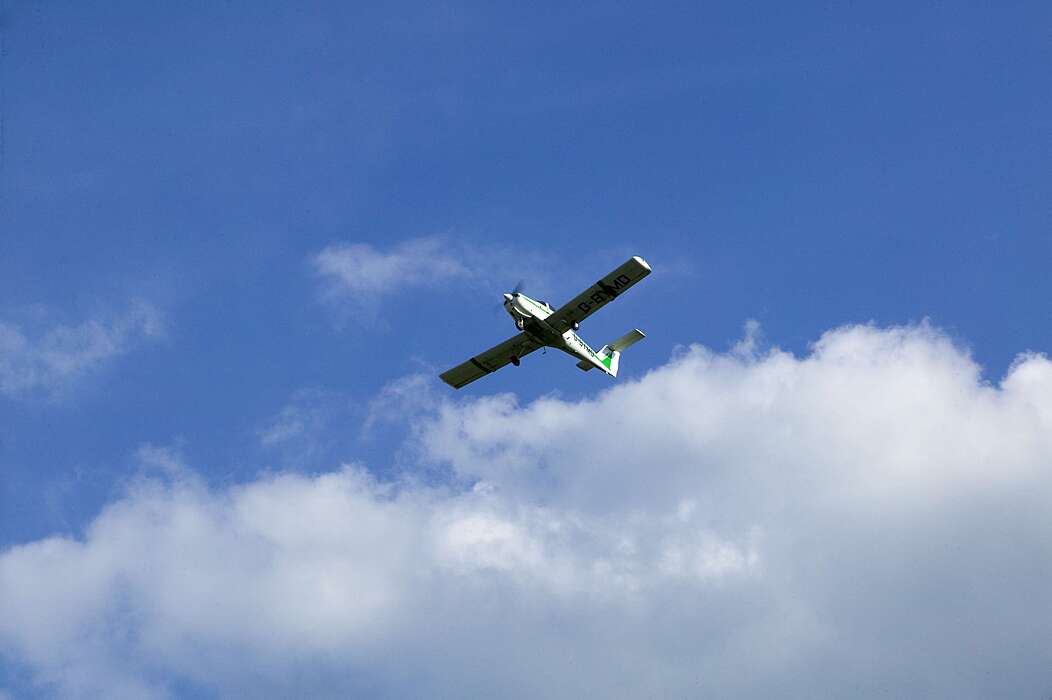 sporting aircraft above in the blue sky with white clouds doing flying lessons at Bede's Summer School