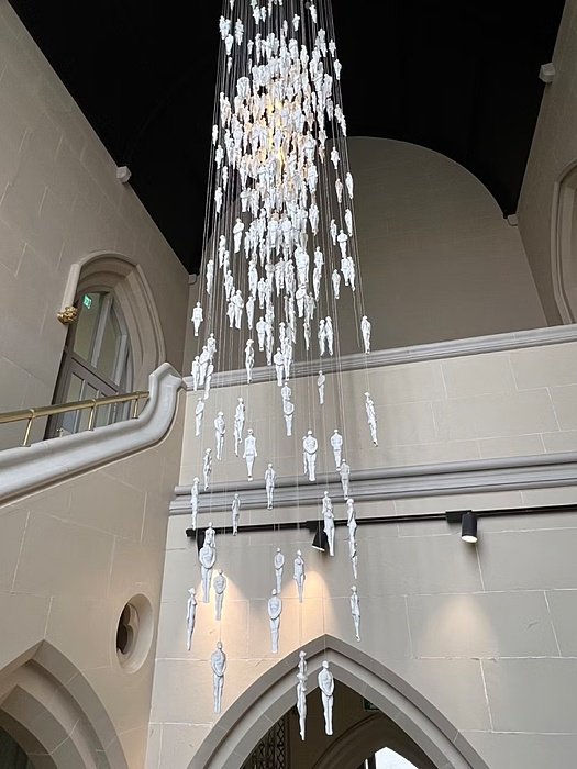 several meter long piece of art hanging from the ceiling in the staircase of the main house