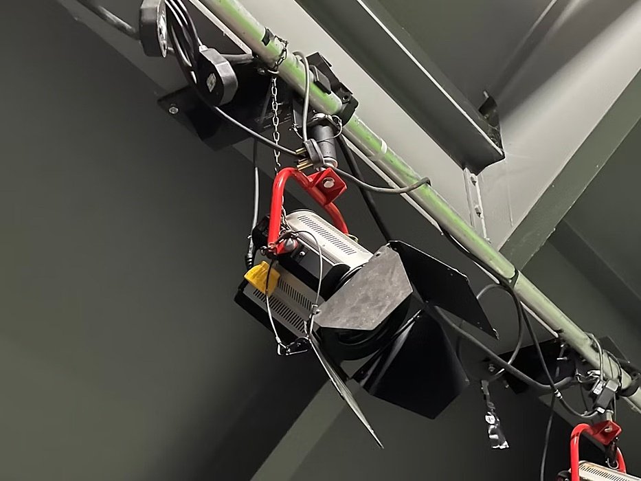 Close-up of a stage or studio spotlight fixture mounted on a ceiling beam.