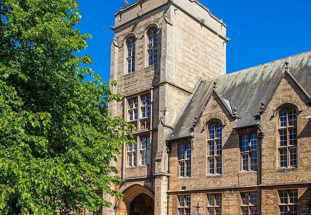 An old school building with a tower and a tree
