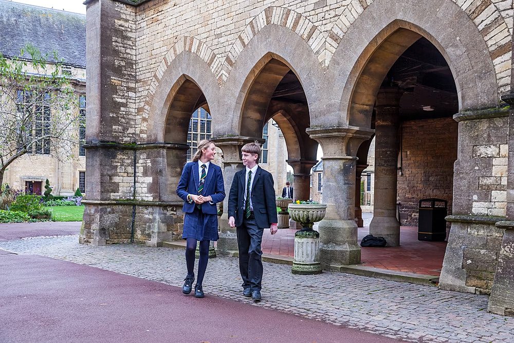 Two pupils walking along old buildings of Uppingham School