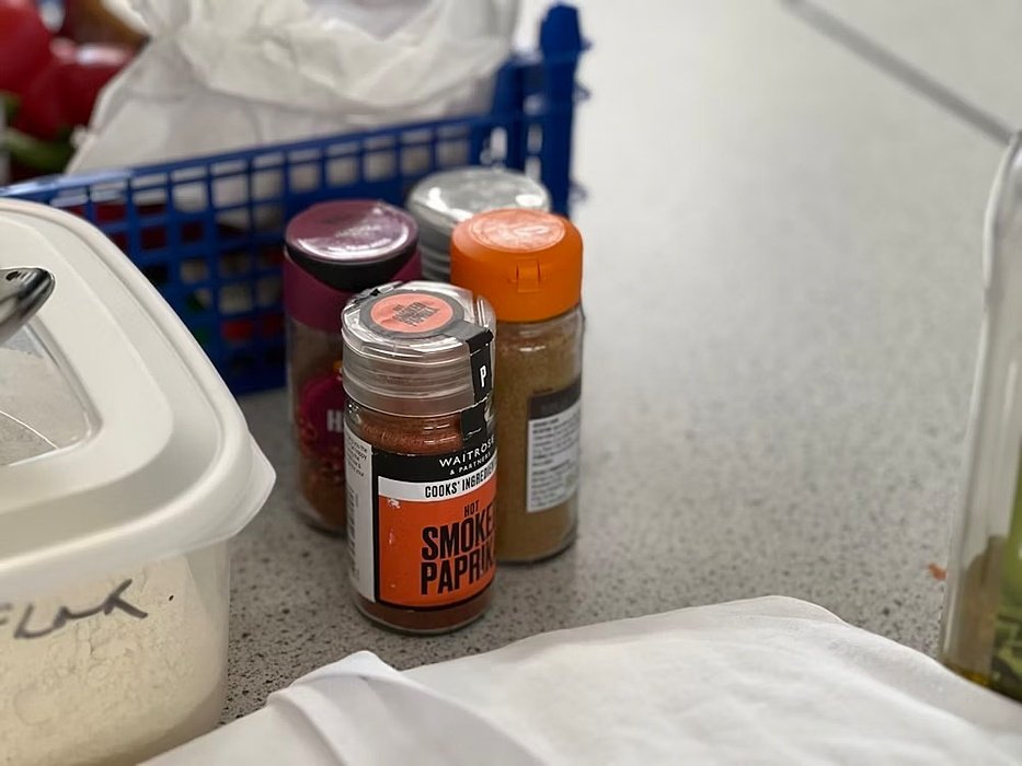 A selection of spice jars, including smoked paprika, on a kitchen counter.