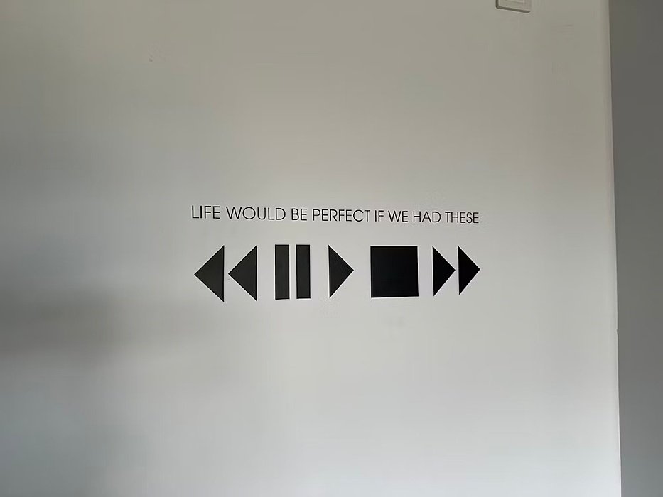 Wall tattoo with a stop, play and fast forward and rewind button saying "Life would be perfect if we had these"