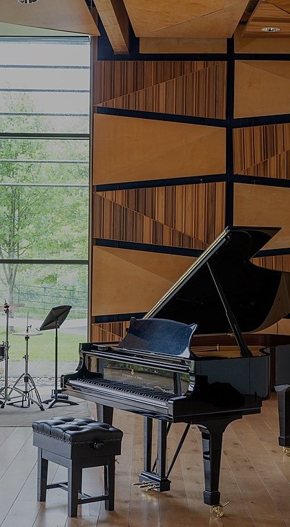 A grand piano and drum set in a beautiful modern wood-paneled audition room
