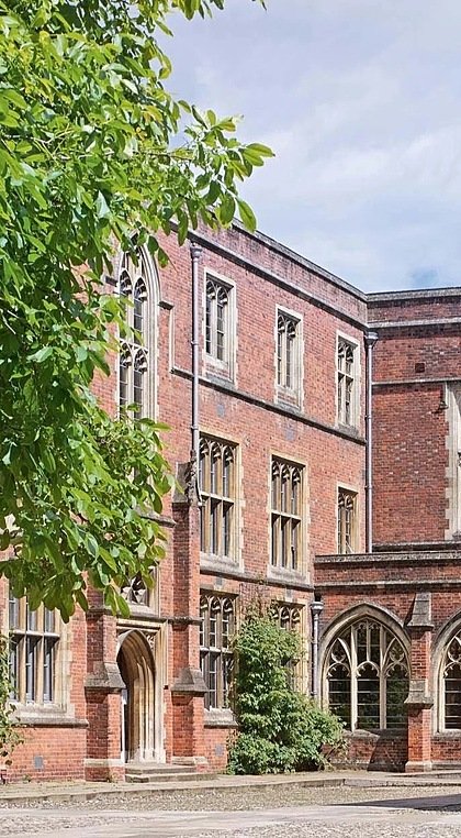 Old red-brick school house with sand-brick arches and trees