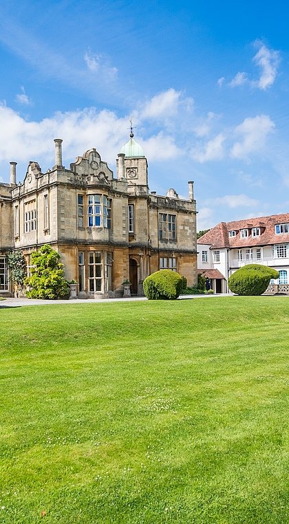 Beautiful manor house with green lawns in front on a blue skied day