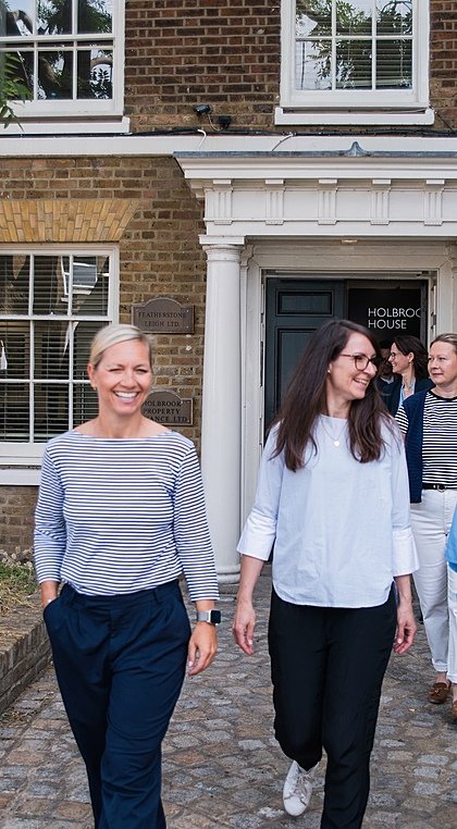 A group of people walking and chatting happily outside a brick building labeled “Holbrook House.”