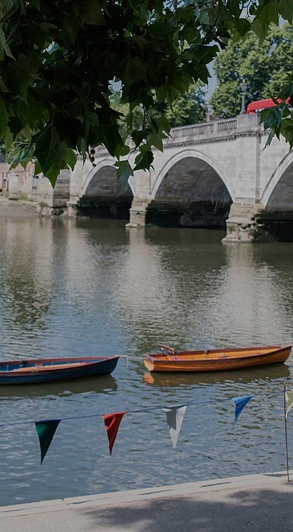 View onto Richmond Bridge with a red bus on it and rowing boats in the water