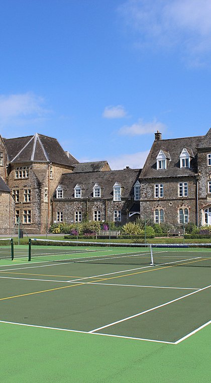 School campus with tennis courts in front and dark-tiled school houses in the back
