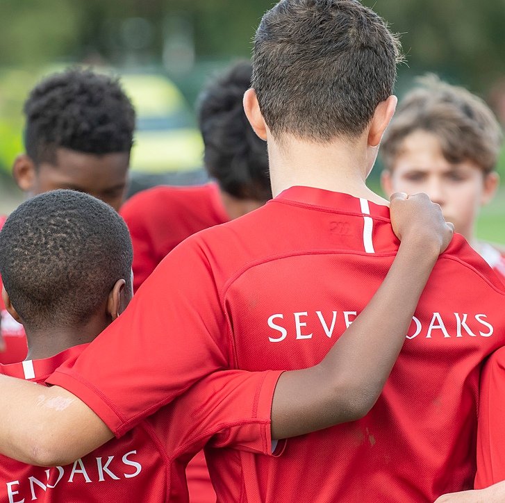 players in their red jerseys branded with the logo of Sevenoaks School