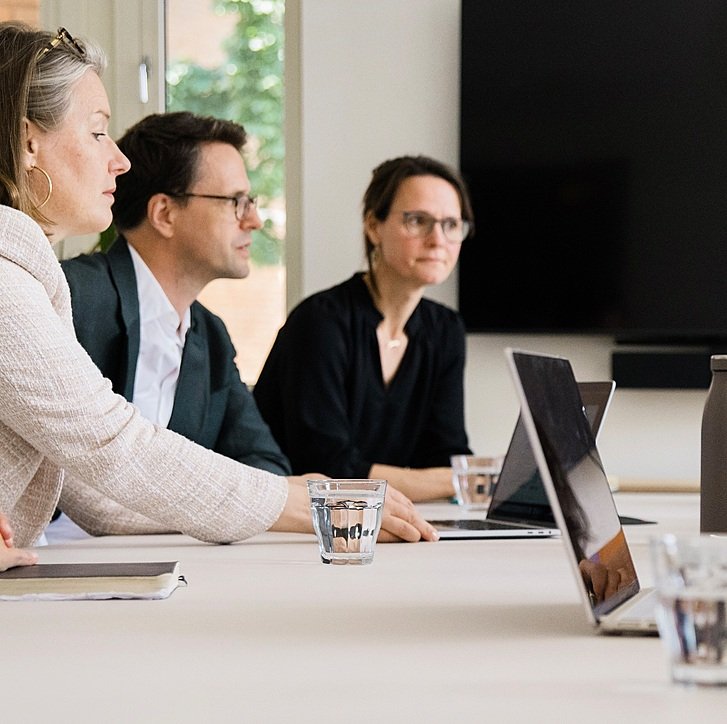 vBE Close-up of three team member sitting at a table talking