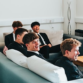 Boys in school uniform sitting in common room laughing