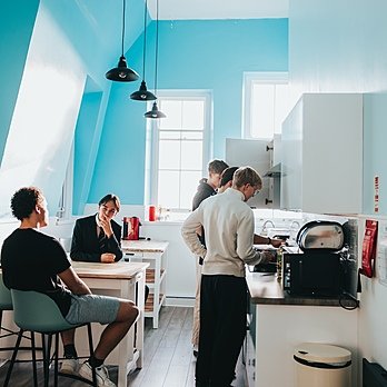 A boarding house kitchen with five boys talking and eating