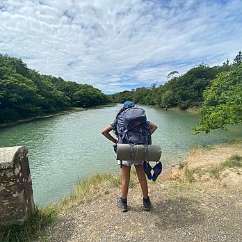 A Ryde School pupil with backpack looking at a lake