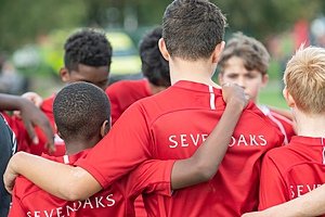 players in their red jerseys branded with the logo of Sevenoaks School