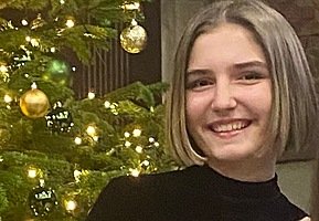 Pupil Charlotte in front of a Christmas tree with baubles