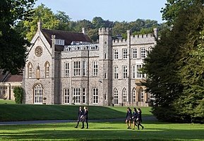 Old stately estate with a green lawn and students