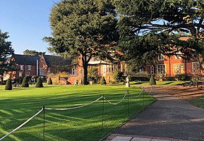 Big red brick building in background with green infront and two trees