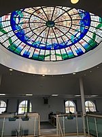 A circular stained-glass dome in blue and green spans a large interior space.