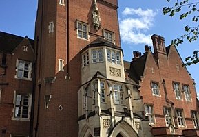 Tall red-brick building with a detailed stone entrance, arched windows, and decorative carvings.