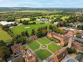 Aerial view of an expansive school campus with sports fields, academic buildings, and tree-lined paths.
