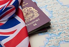 An open atlas with a passport and the British flag placed on top.