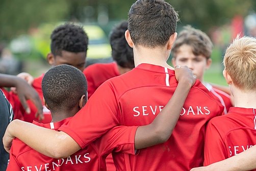players in their red jerseys branded with the logo of Sevenoaks School