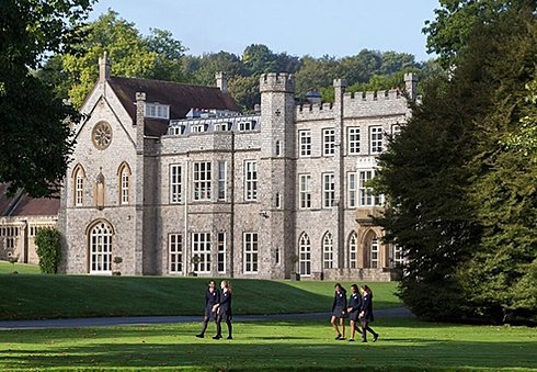 Old stately estate with a green lawn and students