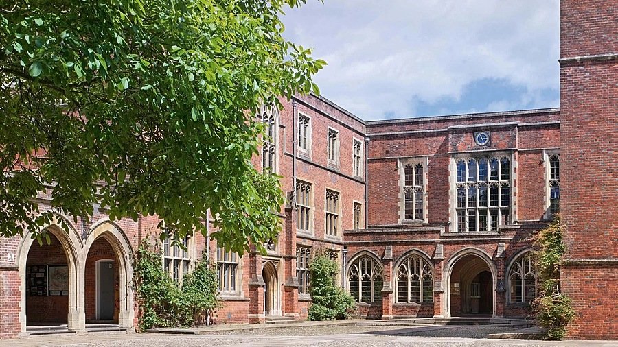 Old red-brick school house with sand-brick arches and trees