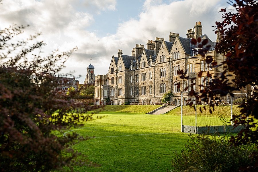 the stunning facade of St Leonards School from the side through bushes on the green campus