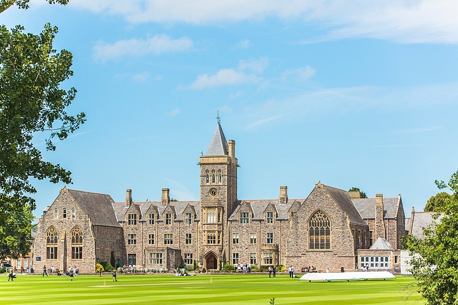 The impressive old buildings of Taunton School from the front with an extensive green pitch in front of its doors
