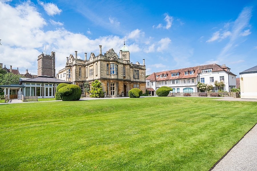 Beautiful manor house with green lawns in front on a blue skied day