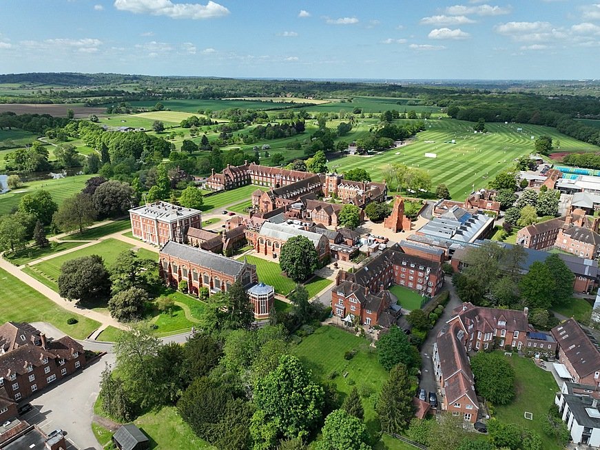 Aerial shot of huge school campus with fancy buildings and green sports fields