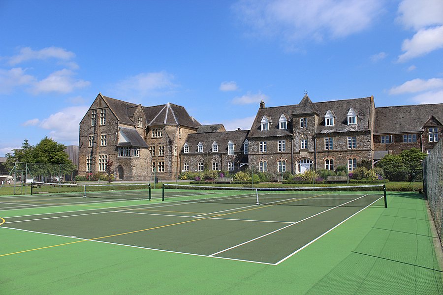 School campus with tennis courts in front and dark-tiled school houses in the back