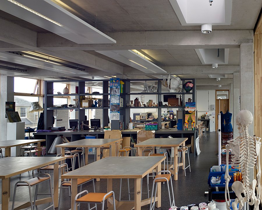 A bright and modern art and design classroom with tables, stools, and creative projects on display.