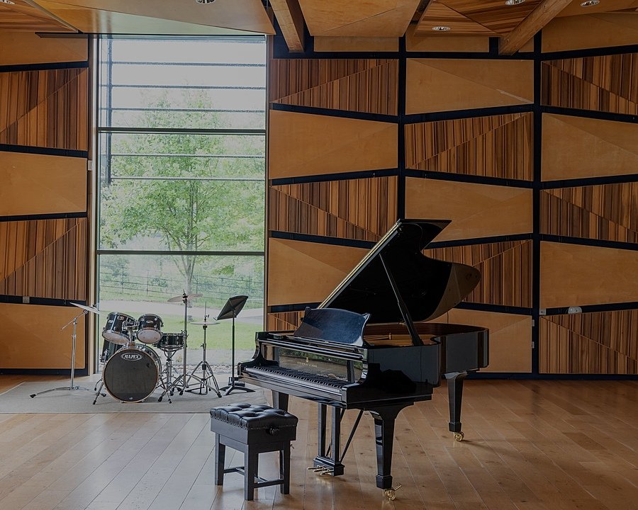 A grand piano and drum set in a beautiful modern wood-paneled audition room