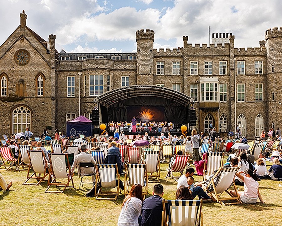 People sitting in beach chairs in front of a big stage where a music production is taking place