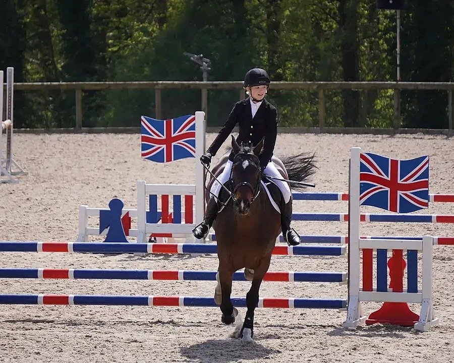 Girl in equestrian uniform on a horse, jumping over an obstacle